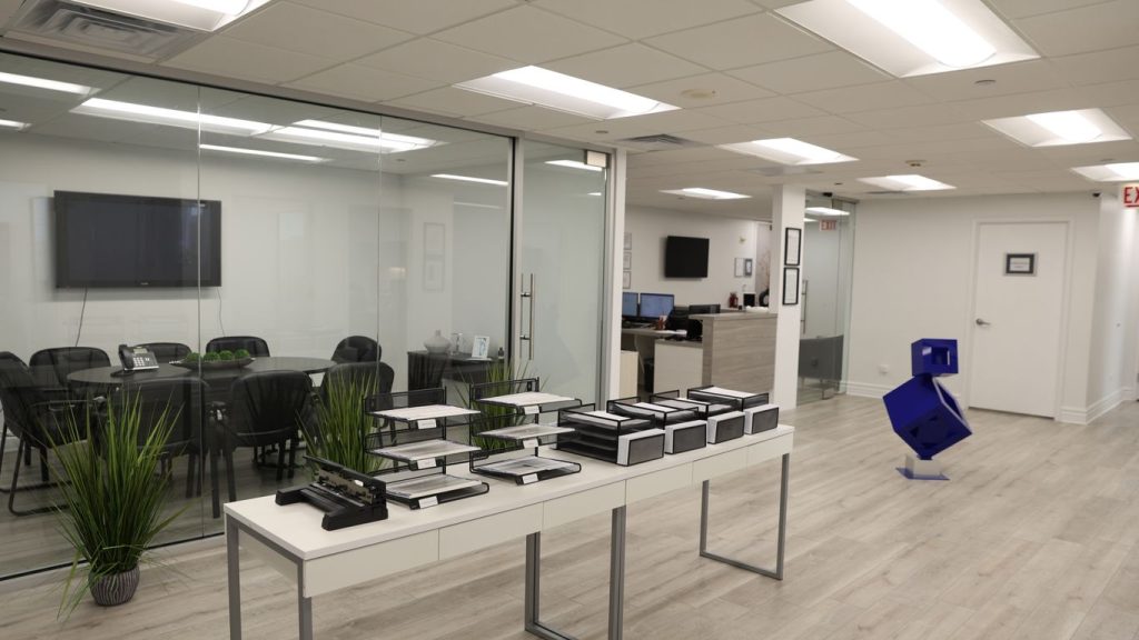 Modern office with conference room, desks, and abstract sculpture.