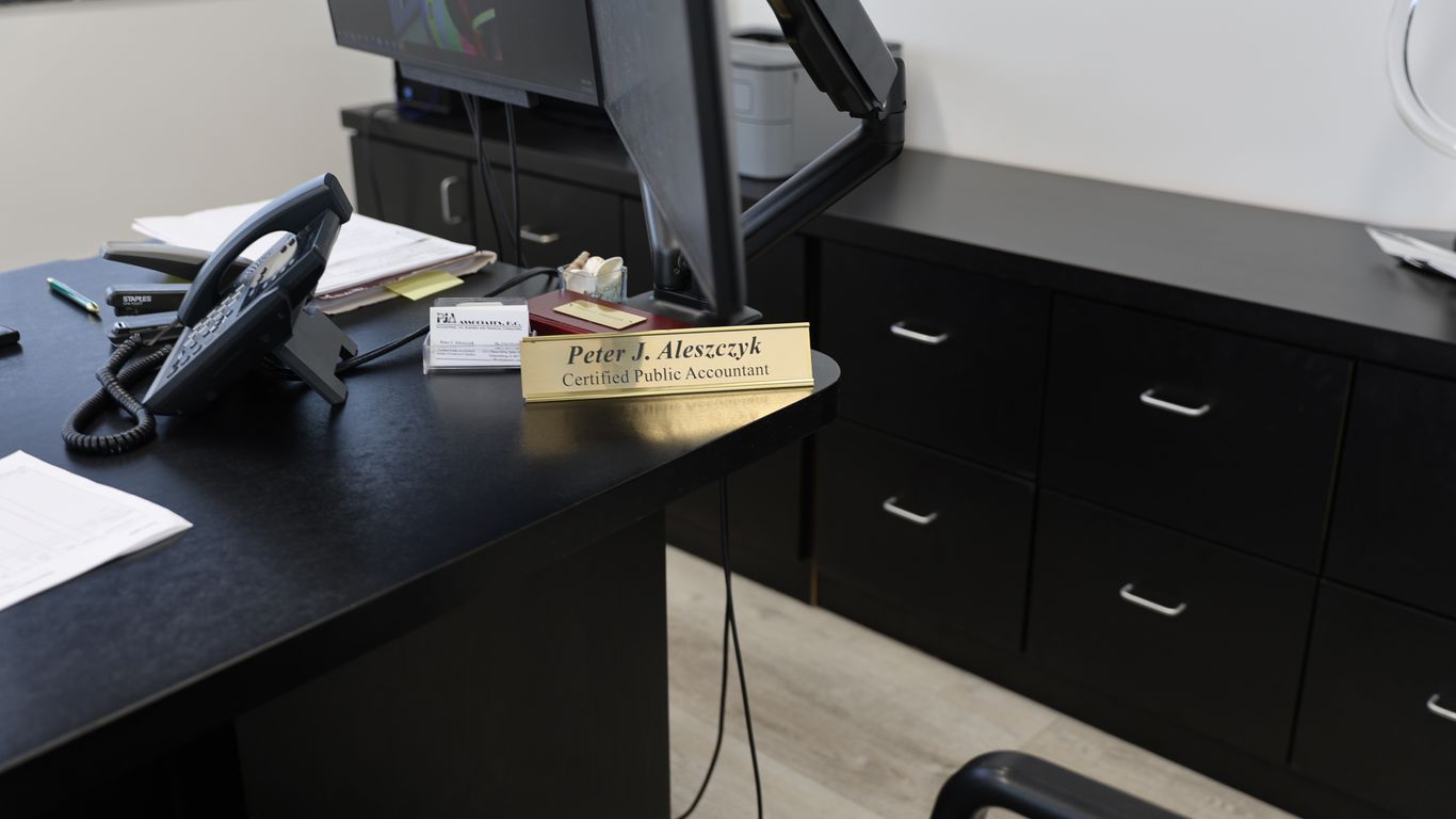 Desk with phone, computer, and nameplate of a certified public accountant.